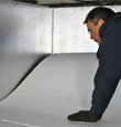 A contractor installing TerraBlock™ floor insulation in a Vanier crawl space