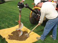 Auguring a hole in the earth for a foundation wall repair system in Vanier