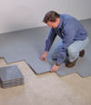 Contractors installing basement subfloor tiles and matting on a concrete basement floor in Kanata, Ontario